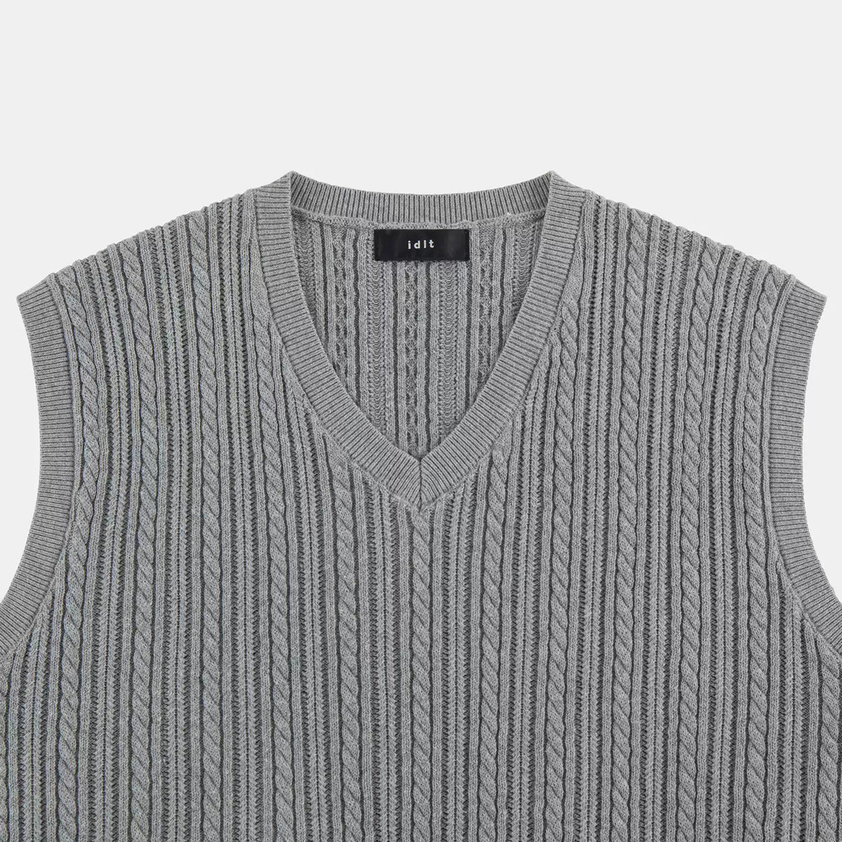 IDLT cable knit vest, gray V-neck close-up.