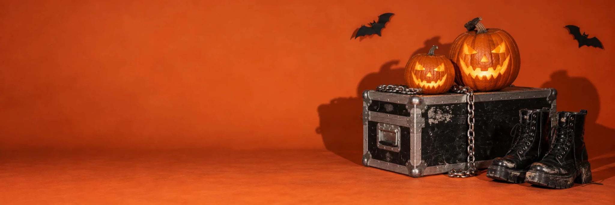 Carved pumpkins, black boots and a flight case on an orange studio backdrop